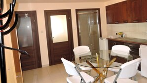 A modern kitchen with wooden cabinets, a glass door, and a round glass table with white chairs. - Holiday Home in a Quiet Location in Borzyslawiec (Goleniow)