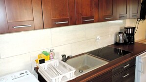 A kitchen with wooden cabinets, a double sink, a coffee maker, and a dish rack. - Holiday Home in a Quiet Location in Borzyslawiec (Goleniow)