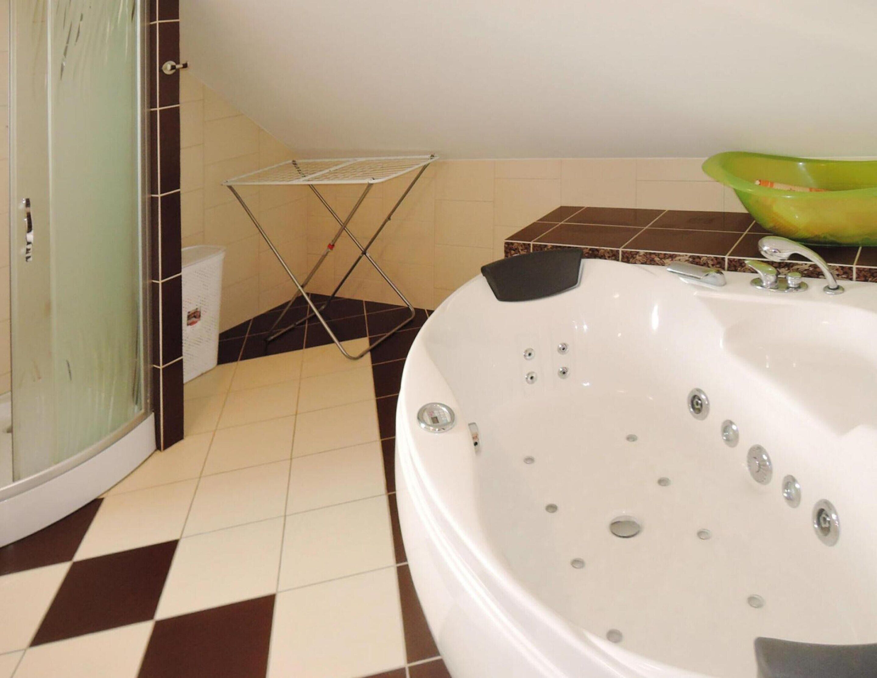 A bathroom with a white bathtub, a glass shower enclosure, and a tiled floor.
