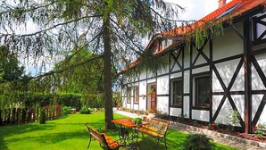 A traditional half-timbered house with a well-maintained garden, a wooden bench, and a table. - Apartment in Darlowo Near Seaside Beach (Darlowo)