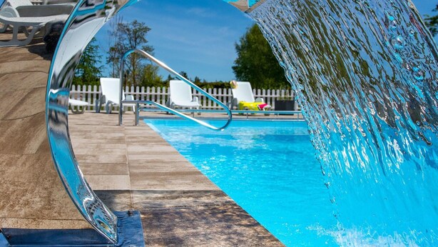 A swimming pool with a clear water feature and a white fence in the background. - Apartment in Darlowo Near Seaside Beach (Darlowo)