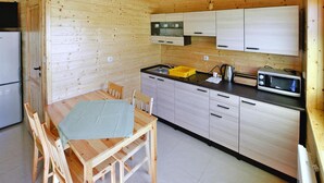 A compact kitchen with wooden cabinets, a microwave, a kettle, and a sink. - Comfortable Holiday Homes Close to the Beach (Mielno)