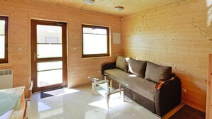 A wooden interior with a sofa, a glass coffee table, and a door leading outside. - Comfortable Holiday Homes Close to the Beach (Mielno)