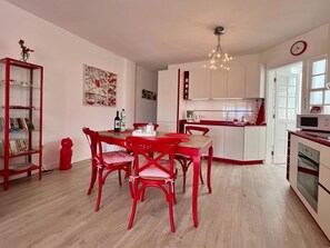 A modern kitchen with white cabinets, a dining area with red chairs, and a red bookshelf. - Apartment, Los Llanos de Aridane (Los Llanos de Aridane)