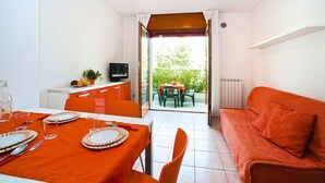 A compact living space with a dining area, a sofa, and a view to an outdoor patio.