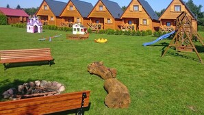 A wooden cabin-style hotel with multiple buildings, a playground, and outdoor seating areas. - Holiday Homes With Terraces, Close to the Beach (Postomino)