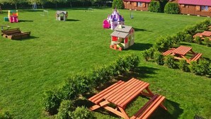 A well-maintained grassy area with play structures, picnic tables, and small wooden cabins. - Holiday Homes With Terraces, Close to the Beach (Postomino)