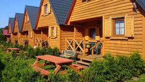 Wooden cabins with pitched roofs, outdoor seating, and a clear sky. - Holiday Homes With Terraces, Close to the Beach (Postomino)