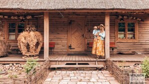 A wooden cabin with a thatched roof, a wooden door, and a porch with steps leading to the entrance.
