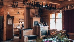 A rustic wooden interior with a fireplace, wooden beams, and a window with curtains.
