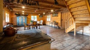 A rustic wooden cabin interior with a dining area, a blue cabinet, and a staircase.