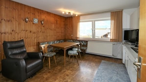 A cozy room with a wooden wall, a leather chair, a wooden table with chairs, a television, and a window with curtains. - Chalet in Fugen Near Spieljochbahn (Fuegen)
