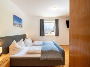 A bedroom with a bed, a bedside table, a nightstand, a window with curtains, a wall-mounted TV, and a painting. - Chalet in Fugen Near Spieljochbahn (Fuegen)