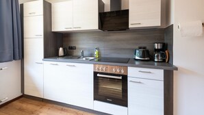 A modern kitchen with white cabinets, a built-in oven, a coffee maker, and a kettle. - Chalet in Fugen Near Spieljochbahn (Fuegen)