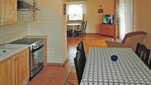 Ett kök med träskåp, en spis och en matplats med ett bord och stolar.