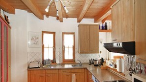 A kitchen with wooden cabinets, a double sink, a stove, and a microwave.