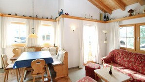 A cozy room with a wooden dining table, chairs, a sofa, and a small table with a vase.