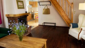 A living room with a fireplace, wooden flooring, a staircase, and a view into the kitchen. - Large Holiday House With Terrace, Bobolin (Darlowo)