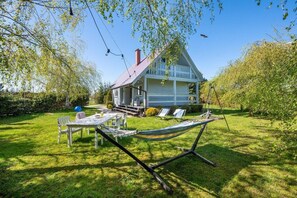 A house with a porch, a hammock, and a table with chairs in the backyard. - Large Holiday House With Terrace, Bobolin (Darlowo)