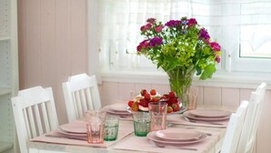 A dining table set with pink placemats, plates, and glasses, surrounded by white chairs. - Large Holiday House With Terrace, Bobolin (Darlowo)
