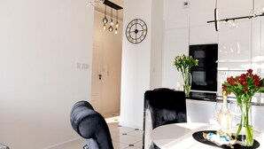 A modern dining area with a round table, black chairs, and a chandelier.
