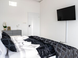 A bedroom with a bed, a dresser, a TV, and a door. - Apartment by Dziwna River With Pool Access (Dziwnów)