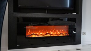 A modern fireplace with a flat-screen TV above it.