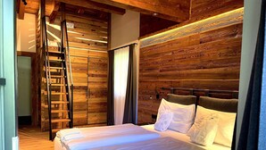 A bedroom with a wooden headboard, a ladder, and a bed with white linens. - Chalet in Saalbach With Panoramic Sauna (Saalbach-Hinterglemm)