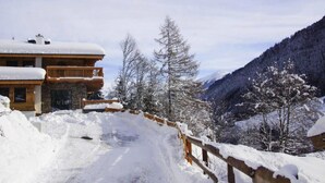 A snow-covered mountain road leading to a wooden lodge with a balcony. - Chalet in Saalbach With Panoramic Sauna (Saalbach-Hinterglemm)