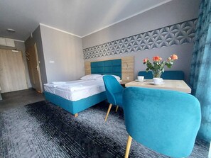 Una habitación de hotel con cama, una mesa con sillas, un jarrón con flores y una pared con diseño.