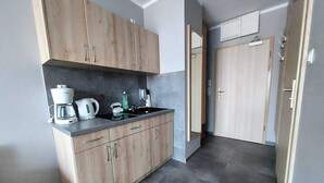 A modern kitchen with wooden cabinets, a coffee maker, and a sink. - Studio in Poland Near Beach Promenade (Swinoujscie)