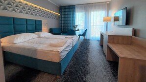 A hotel room with a large bed, a desk, a chair, a TV, and a window with curtains. - Studio in Poland Near Beach Promenade (Swinoujscie)