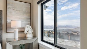Un bagno moderno con un'ampia finestra, un quadro astratto incorniciato, un vaso bianco e una piccola pianta.
