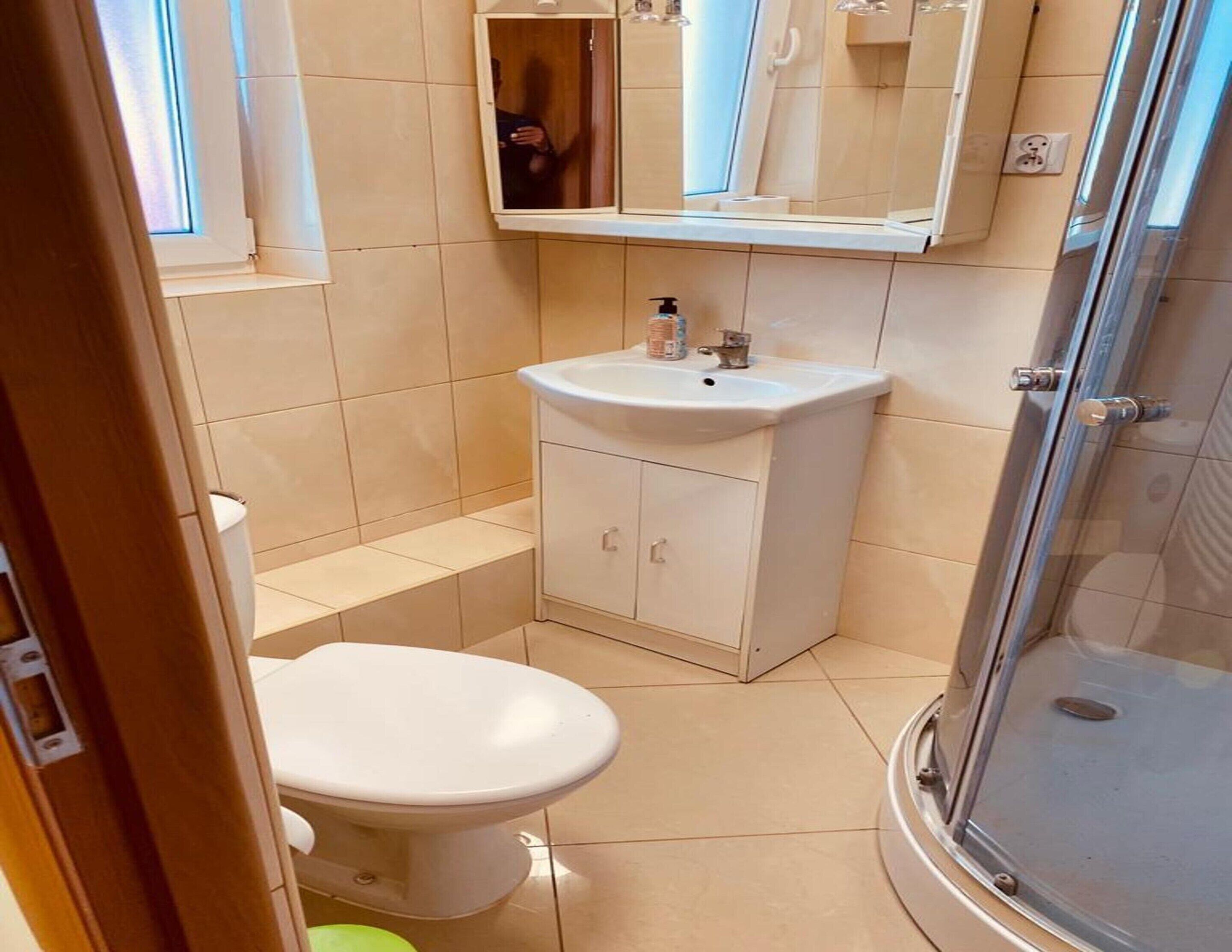 Egy kis méretű fürdőszoba, amelyben WC, mosdókagyló és zuhanyzó található.