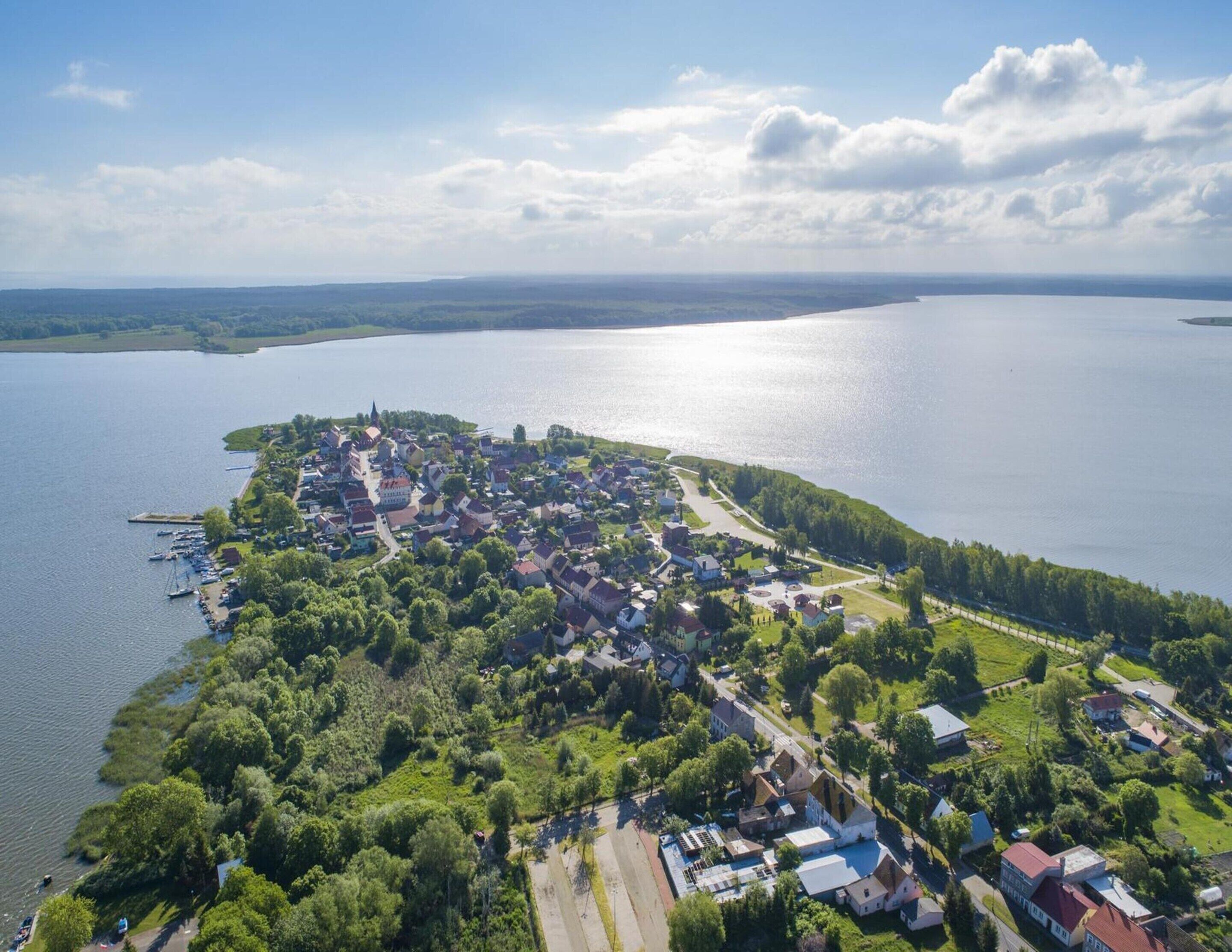 An aerial view of a lakeside town with residential buildings, a marina, and a church.