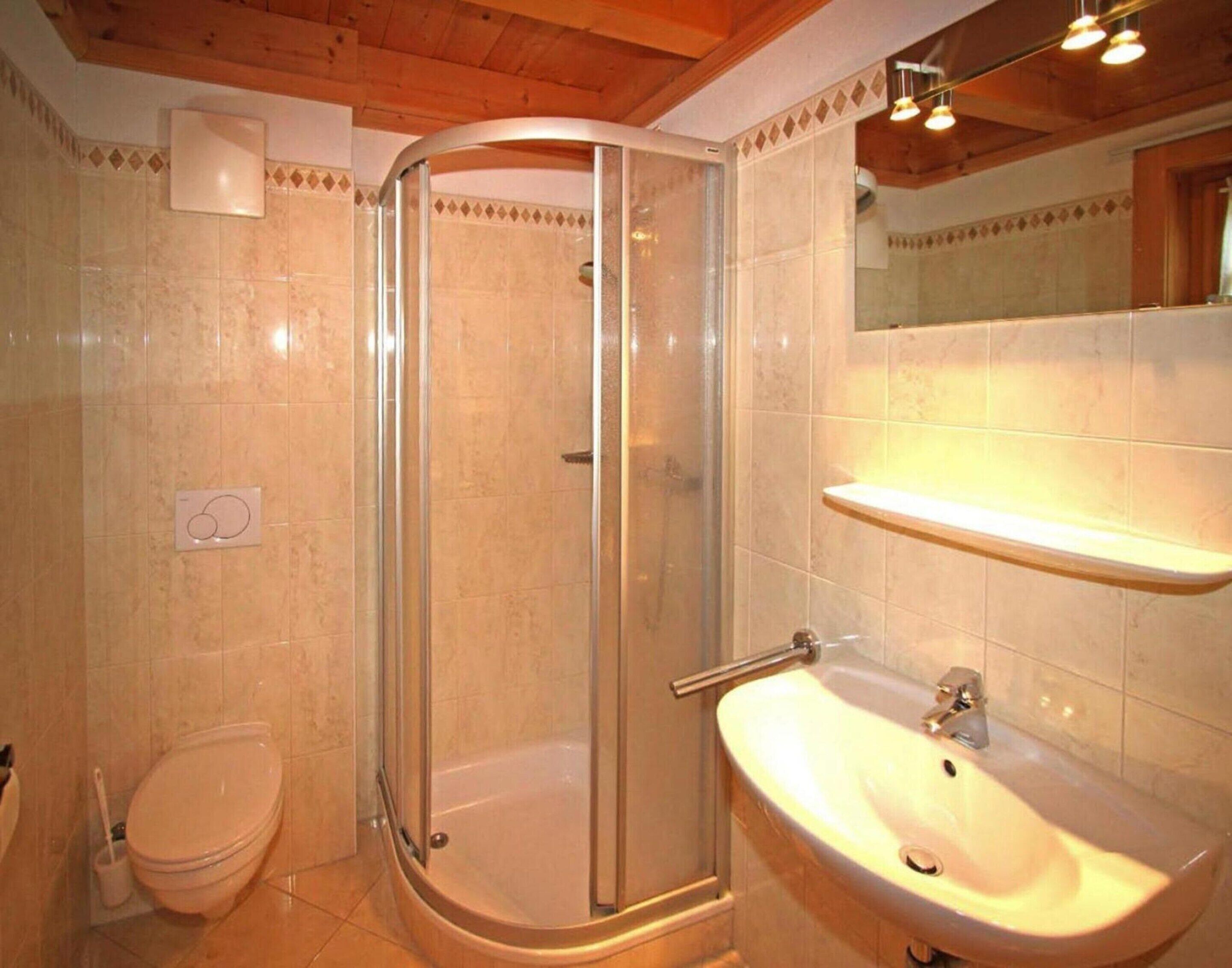 A bathroom with a glass-enclosed shower, a toilet, and a sink.
