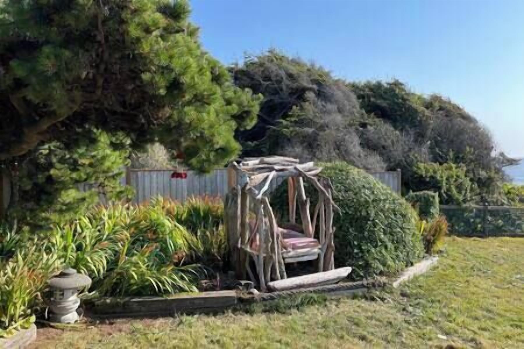 A garden with a wooden swing set and a stone lantern.