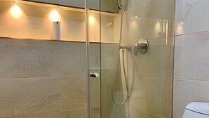 Un baño moderno con ducha de vidrio, inodoro blanco y suelo de mármol.