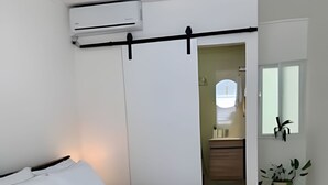 Una habitación de hotel moderna con una cama, una mesita de noche, una planta en maceta y un ventanal.