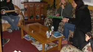 A cozy living room with a television, a lamp, and a piano. - Hostal Bellavista Patagonia (Natales)