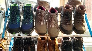 A rack of various types of footwear, including hiking boots and casual shoes, arranged on shelves. - Hostal Bellavista Patagonia (Natales)