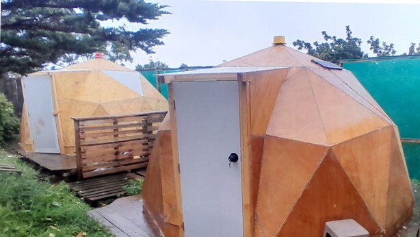 Two hexagonal metal structures with a door and a small stool, likely serving as storage or utility rooms. - Hostal Bellavista Patagonia (Natales)
