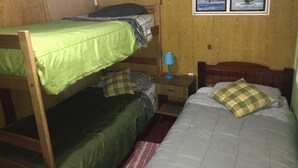 A bunk bed room with a wooden headboard, a nightstand with a lamp, and two framed pictures on the wall. - Hostal Bellavista Patagonia (Natales)