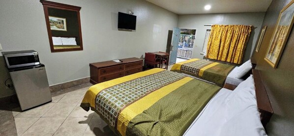 Habitación de hotel con dos camas, un escritorio, un aparador, un microondas y un televisor.