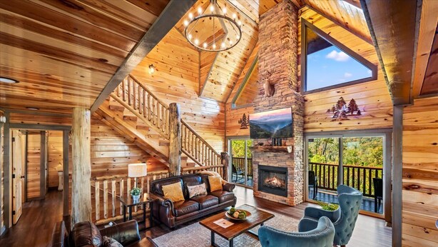 A spacious log cabin interior with a fireplace, leather furniture, and a balcony with a scenic view. - Indoor Pool, Volleyball Beach, Mountain View (Gatlinburg)
