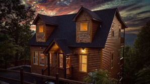 A log cabin with a porch, multiple windows, and a stone foundation. - Views, Indoor Pool, Luxury Cabin, Bears (Gatlinburg)