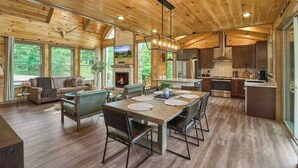 A spacious living area with a fireplace, a dining table with chairs, and a kitchen area with modern appliances. - Views, Indoor Pool, Luxury Cabin, Bears (Gatlinburg)