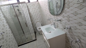 Une salle de bain avec une douche à parois de verre, des toilettes et un lavabo avec un miroir au-dessus.