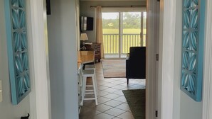 A hallway leading to a balcony with a ceiling fan, a TV mounted on the wall, and a staircase. - Beautiful, Newly-Renovated Condo on the Altamaha River in Darien with BoatSlip (Darien)