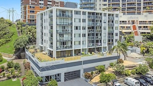 Un hotel de varios pisos con balcones, un jardín en la azotea y un área de estacionamiento.